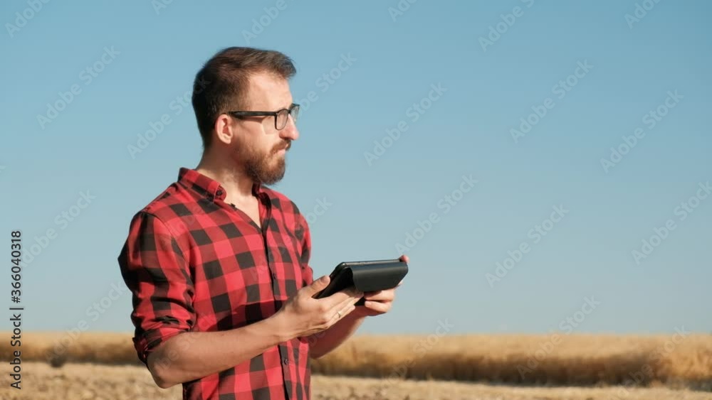 Man With Tablet On the Field, Modern Farming Concept. Male millennial person with a tablet computer standing in the rye or wheat field, concept of modern agricultural business, IT in farming Man With Tablet On the Field, Modern Farming Concept. Male millennial person with a tablet computer standing in the rye or wheat field, concept of modern agricultural business, IT in farming
