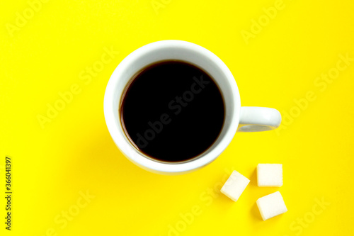 Black coffee with pieces of sugar in a white cup