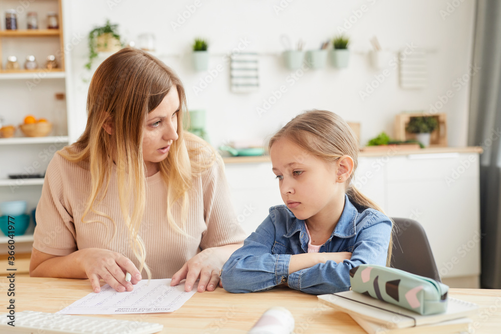 Warm-toned portrait of frustrated mother talking to little girl while doing homework or studying at home, copy space Warm-toned portrait of frustrated mother talking to little girl while doing homework or studying at home, copy space
