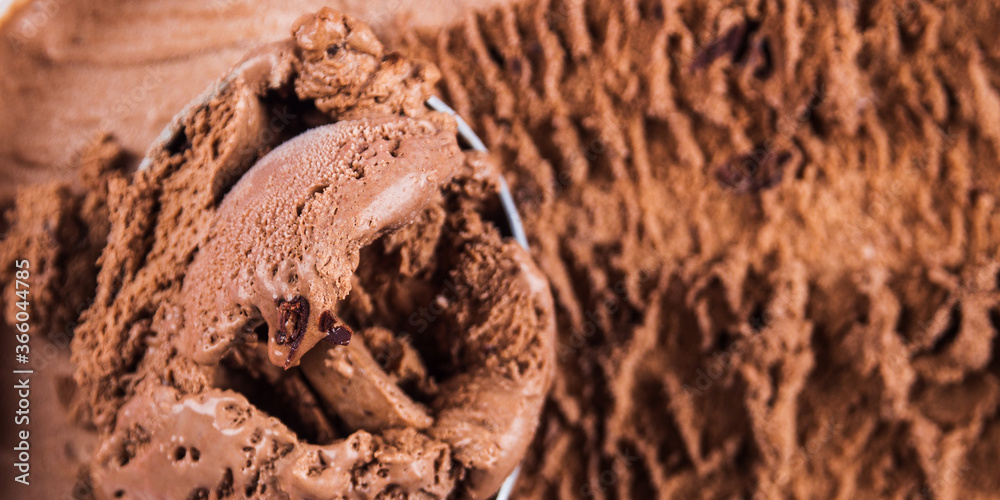 Full ice cream scoop in chocolate ice cream tub. Macro texture banner Full ice cream scoop in chocolate ice cream tub. Macro texture banner