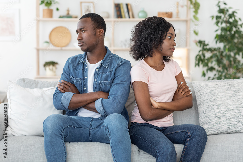 Offended black husband and wife sitting on couch at home Offended black husband and wife sitting on couch at home