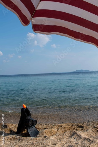 Beach view with an umbrella. Wallpaper, copy space. Island in the background