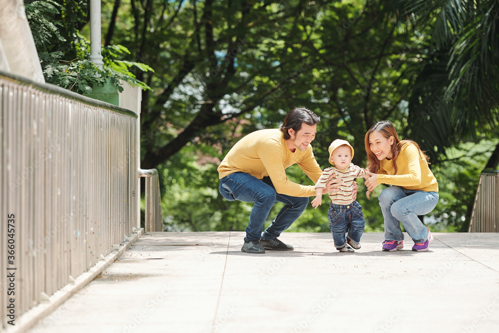 Happy young parents trying to catch their child who is trying to run away Happy young parents trying to catch their child who is trying to run away