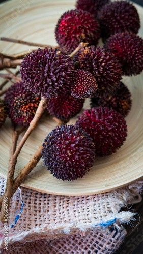 The exotic pulasan tropical fruit or scientific name Nephelium Mutabile on a wooden plate. Selective focus. photo