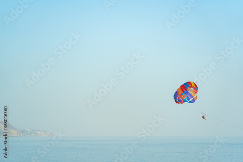 paragliding couple doing extreme sport in the middle of the ocean with beautiful blue sky
