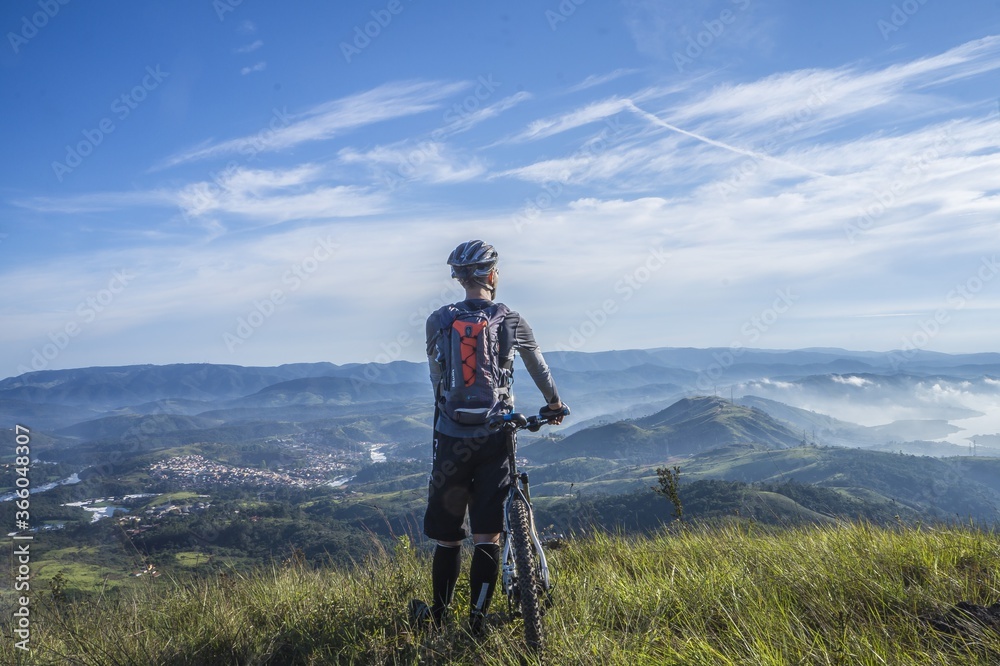cyclist enjoying the landscape from the top of the mountain with his bicycle
