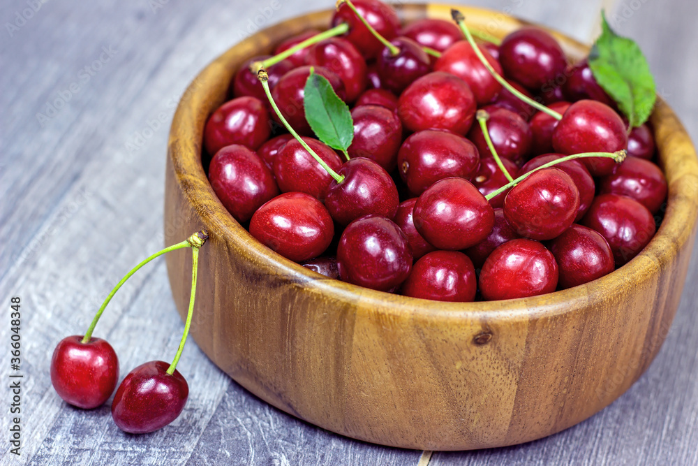 Fresh juicy red sweet cherry berries in the wooden bowl on light background in summer.