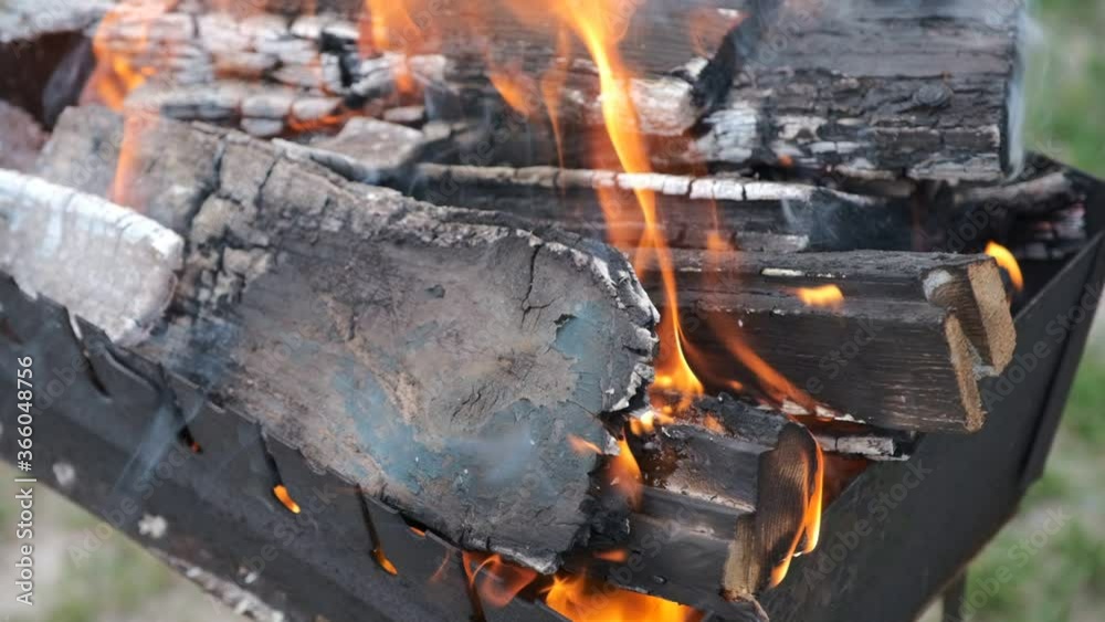 lames from burning slices wood in mangal. Bonfire inside metal brazier. Firewood burns to preparation for cooking barbecue. Slow motion