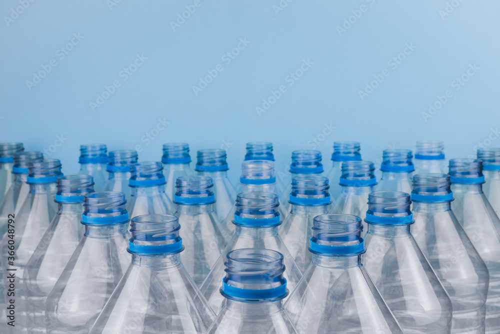 Empty clear plastic bottles without caps stacked on a blue background. Recycling and environment concept. Empty clear plastic bottles without caps stacked on a blue background. Recycling and environment concept.