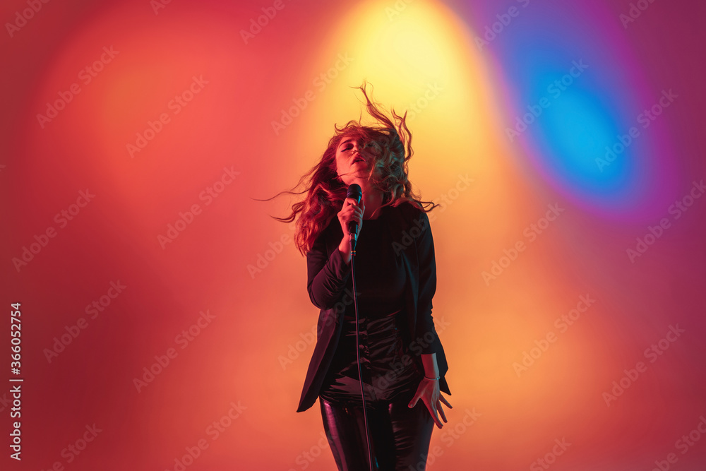 Elegance. Young caucasian inspired and expressive musician, female singer performing on multicolored background in neon. Concept of music, hobby, festival, art. Joyful artist, colorful, bright Elegance. Young caucasian inspired and expressive musician, female singer performing on multicolored background in neon. Concept of music, hobby, festival, art. Joyful artist, colorful, bright