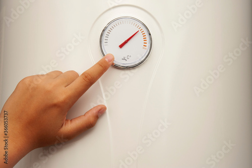 A woman's hand points to a tempurature point on the boiler