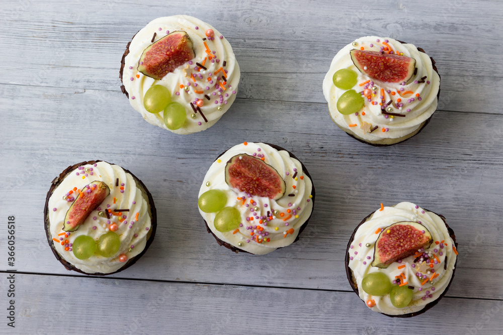 Delicious cupcakes with vanilla cream, figs and grapes.View from Delicious cupcakes with vanilla cream, figs and grapes.View from