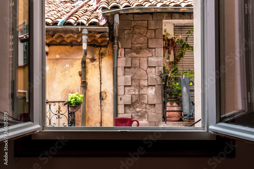 A red cup of fresh black coffee standing on a window sill of an apartment in a French village in the morning