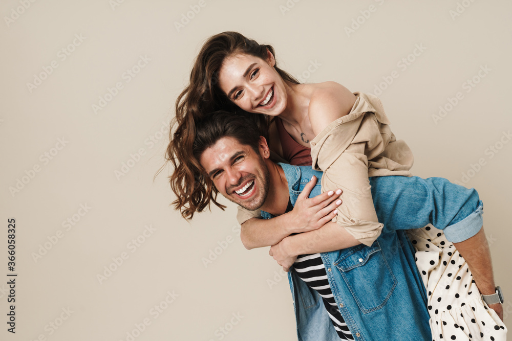 Image of cheerful beautiful couple piggybacking and laughing