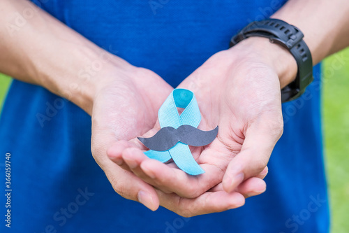 November Prostate Cancer Awareness month, adult Man holding Blue Ribbon with mustache for supporting people living and illness. Healthcare, International men, Father and World cancer day concept