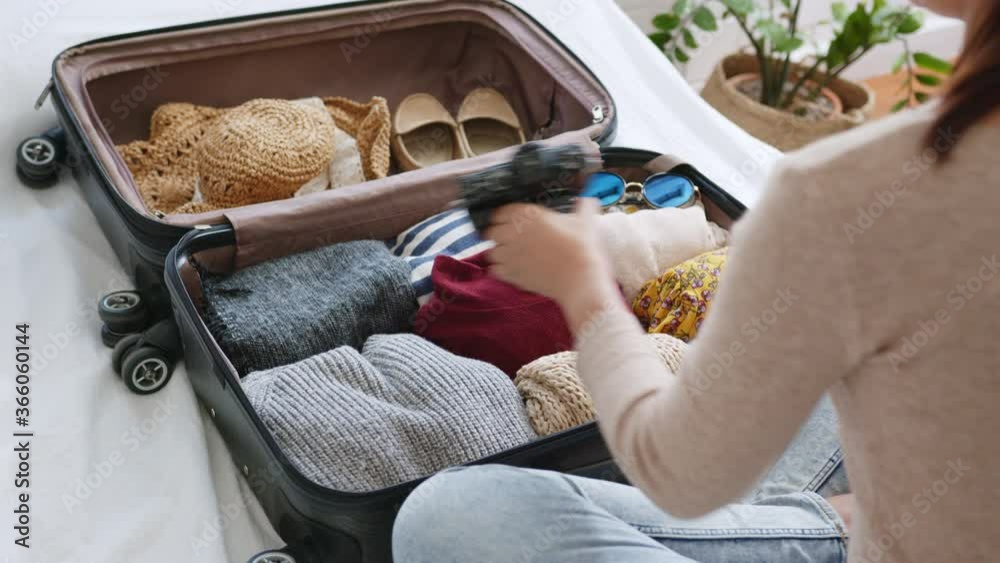 Woman hand packing suitcase luggage including face mask and sanitizer