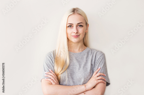 Pretty smiling joyfully female with fair hair, dressed casually, looking with satisfaction at camera, being happy. Studio shot of good-looking beautiful woman