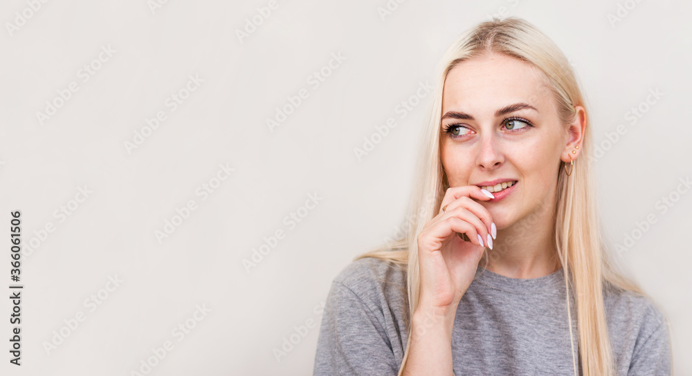 Cute playful young woman smiling and thinking over beige background Cute playful young woman smiling and thinking over beige background