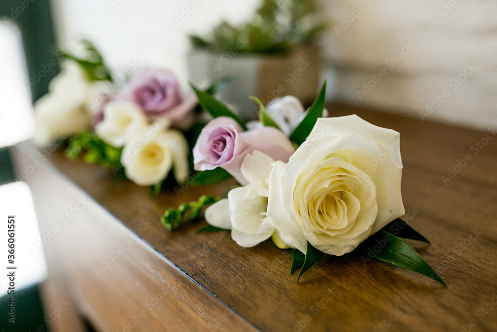 large white and purple rose groom boutonniere or corsages set on table large white and purple rose groom boutonniere or corsages set on table