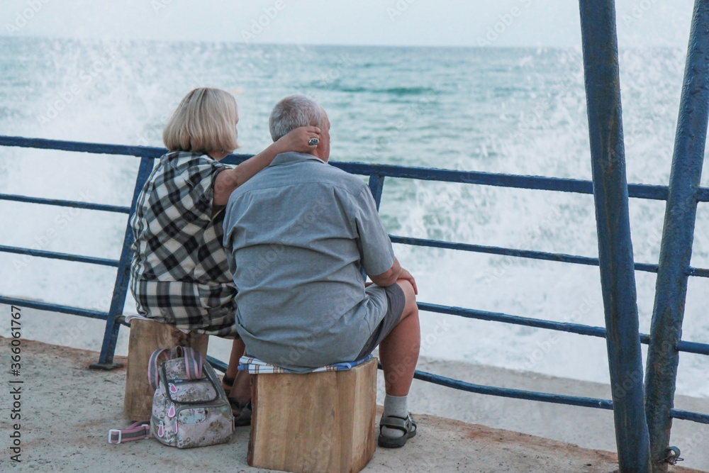 Fototapeta premium an elderly couple sitting on the beach