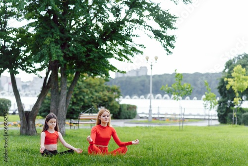 woman and child do yoga in the park. summer, sun, mother and daughter, health. outdoor sports. healthy sport lifestyle. fitness, yoga