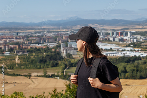 Girl tourist with a backpack looking at old city. Girl standing back and admiring the view of the city. Spain, walk around the city © Olha