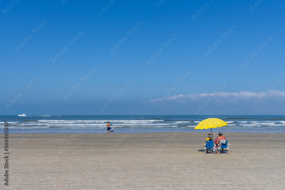 Casal de idosos sentados à beira mar tomando sol e relaxando na praia. Reabertura das praias após quarentena. Casal de idosos sentados à beira mar tomando sol e relaxando na praia. Reabertura das praias após quarentena.