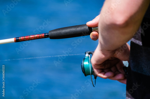 Man on the lake with fishing rod close up in hands with space for text. Fisherman close up with fishing rod, luring the fish. Men fishing with fishing tools.