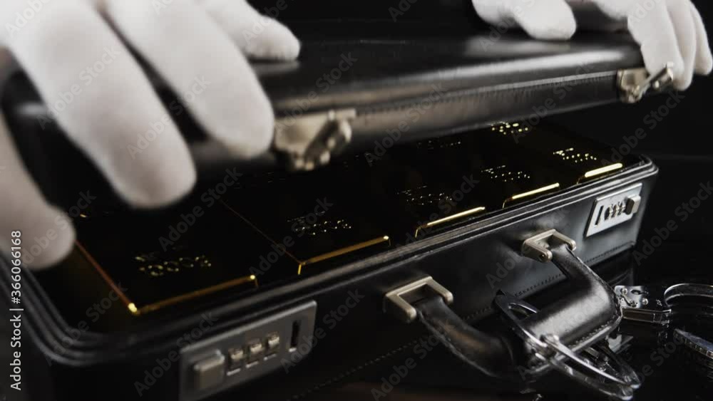 Stack of gold bars. Handcuffed briefcase with pure gold bars. The man in white gloves closes a case full of fine gold bars. Stack of gold bars. Handcuffed briefcase with pure gold bars. The man in white gloves closes a case full of fine gold bars.