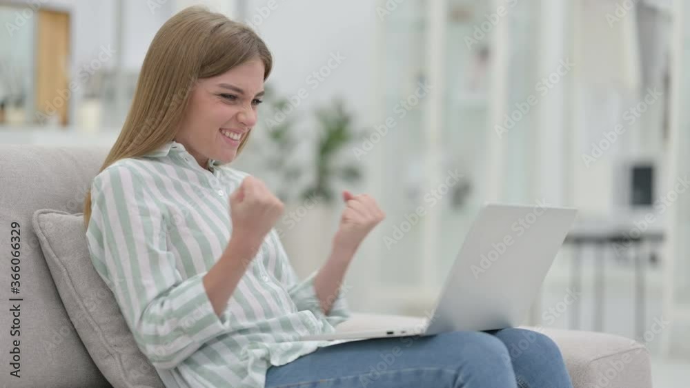 Excited Young Woman Celebrating Success on Laptop at Home 