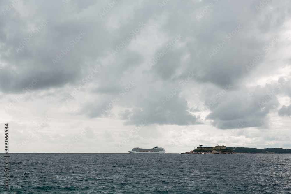 Cruise liner on the horizon, near the island of Mamula in Montenegro. Against the cloudy sky with gray clouds.