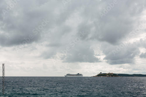Cruise liner on the horizon, near the island of Mamula in Montenegro. Against the cloudy sky with gray clouds. © Nadtochiy
