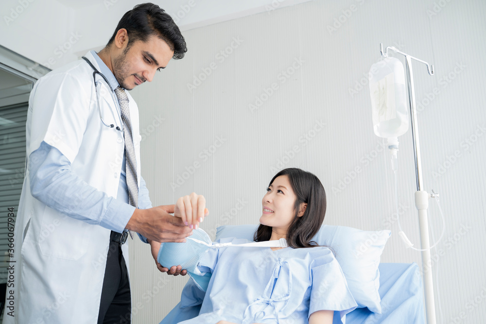 Smiling doctor examining female patient's arm while sitting in medical examination room at clinic. Smiling doctor examining female patient's arm while sitting in medical examination room at clinic.
