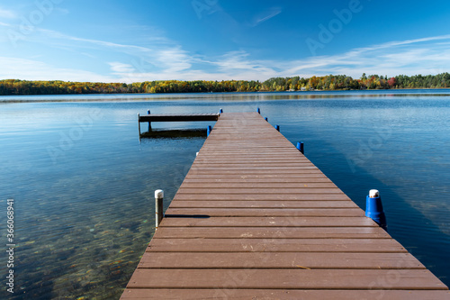 A dock in the lake across from verdant forest on a bright day