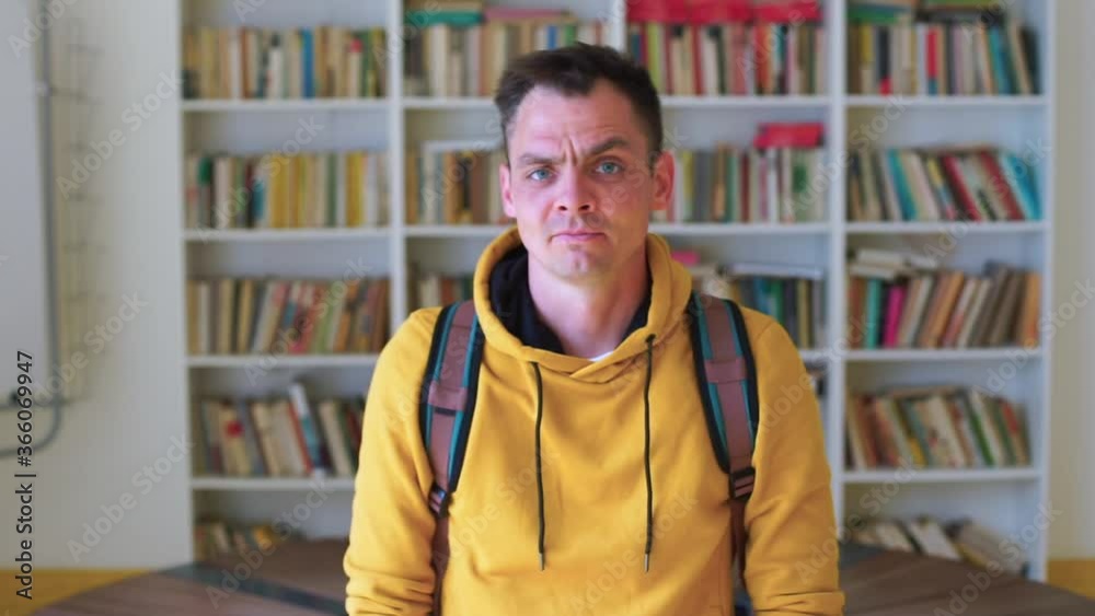 Portrait of an emotional man in the library. The man is posing, looking away. Waiting for a scheduled meeting. Portrait of an emotional man in the library. The man is posing, looking away. Waiting for a scheduled meeting.