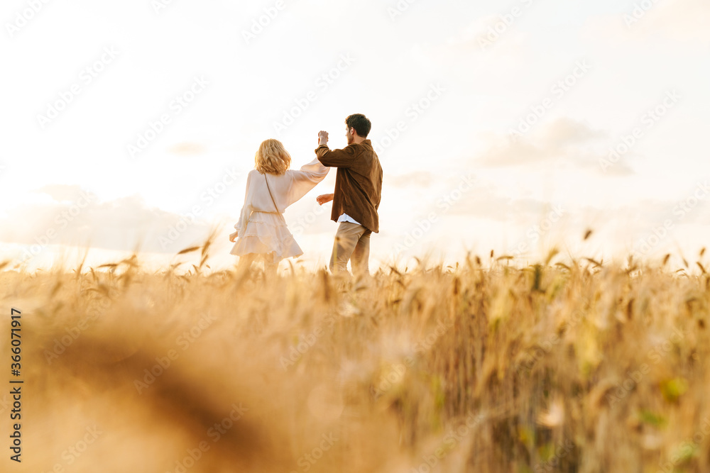 Image of young caucasian couple walking in golden field on countryside