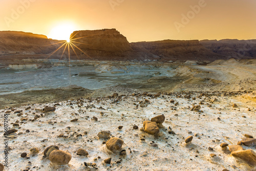 Sun bursts as it sets behind Masada, ancient Jewish fortress in the Judean desert - location of Herod's palaces and of the Roman siege, now one of Israel's most popular tourist attractions; Dead Sea photo