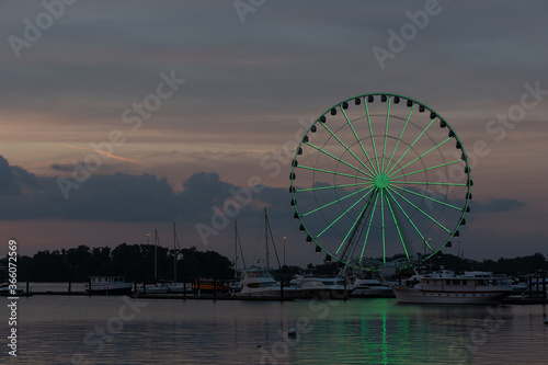 Brightly-lit Ferris wheel at twilight in a harbor © Mark