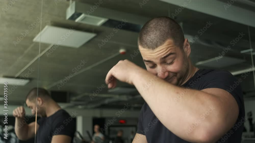 Portrait of an athletic guy with big biceps warming up on a treadmill before a workout in the gym