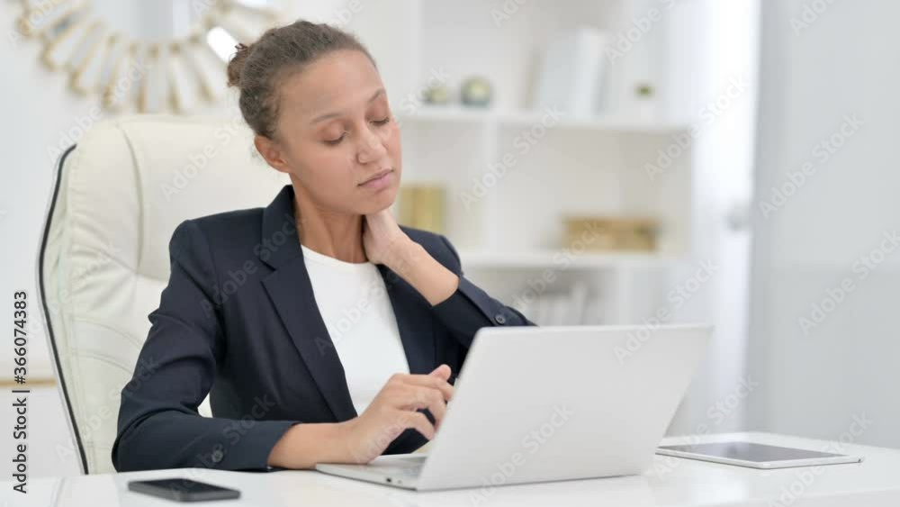 Tired African Businesswoman with Laptop having Neck Pain in Office Tired African Businesswoman with Laptop having Neck Pain in Office