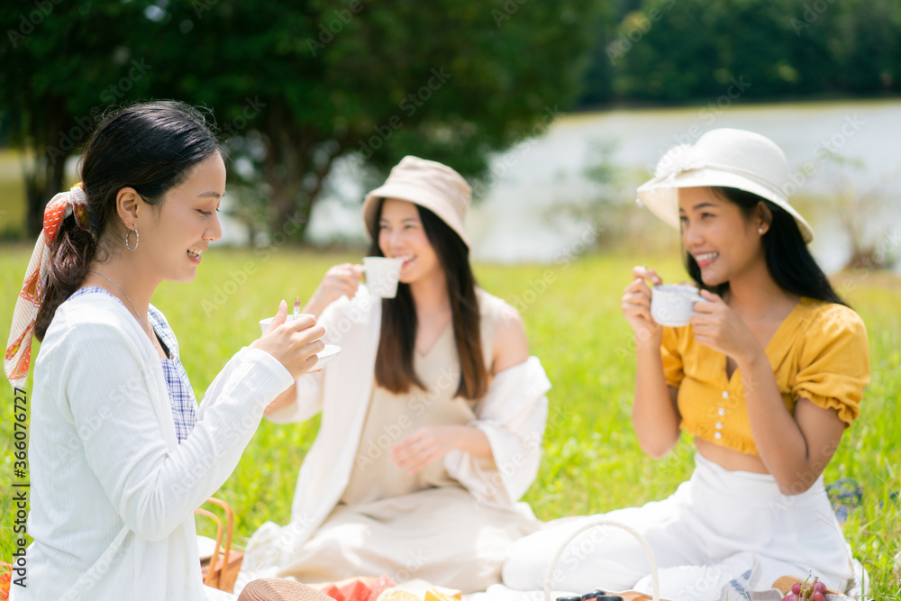 Asian woman friends. They are having a picnic, eating in the morning.They drink coffee. Asian woman friends. They are having a picnic, eating in the morning.They drink coffee.