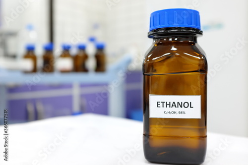 Selective focus of ethanol or ethyl alcohol brown amber glass bottle inside a laboratory. Blurred background with copy space. photo