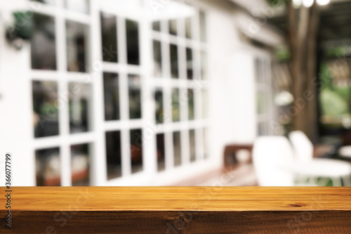 Empty wooden desk space and blurry background of cafe or Restaurant for product display montage.