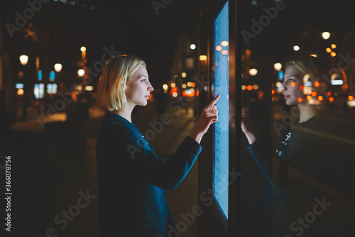 Obraz na plátně Young caucasian woman using a touch sensitive display while standing on the stre