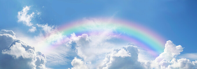 Stunning blue sky panoramic rainbow - big fluffy clouds with a giant arcing rainbow against a  beautiful summer time blue sky with copy space for messages

