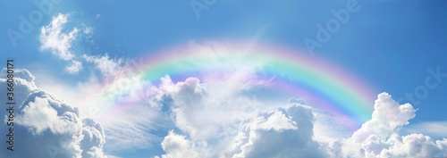 Obraz na plátně Stunning blue sky panoramic rainbow - big fluffy clouds with a giant arcing rain