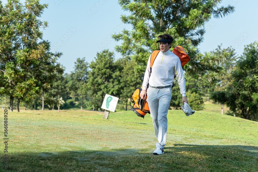 Golfer asian man walking in fairway with bag golf at golf  club.  Hobby in holiday and vacation 