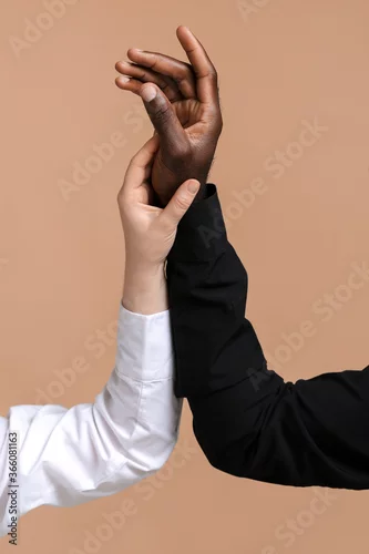 Obraz Caucasian woman and African-American man holding hands together on color background. Racism concept