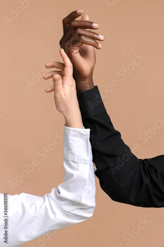 Obraz Caucasian woman and African-American man holding hands together on color background. Racism concept