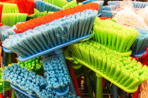 Plastic brushes. Polymer brooms of different colors in a household goods store.